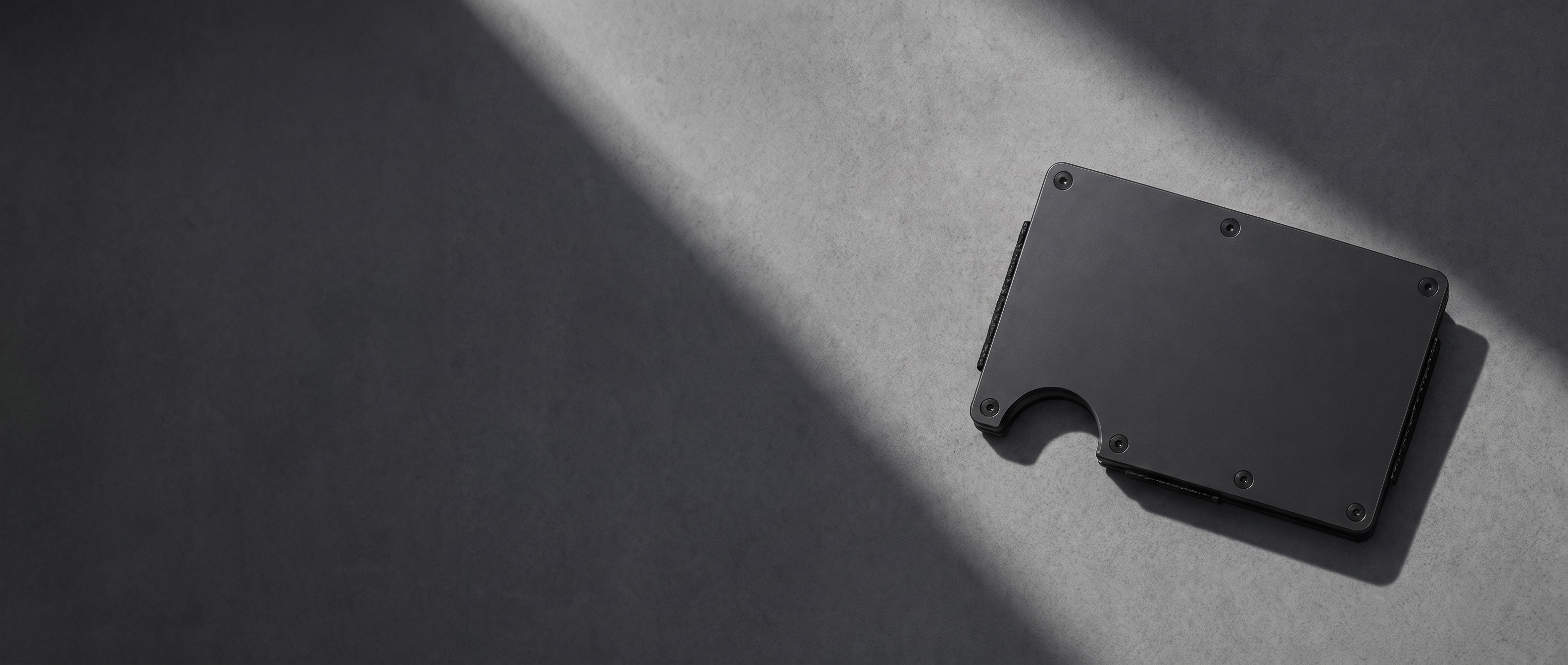 Slimfolio Slimline wallet, black satin finish, on a concrete surface
